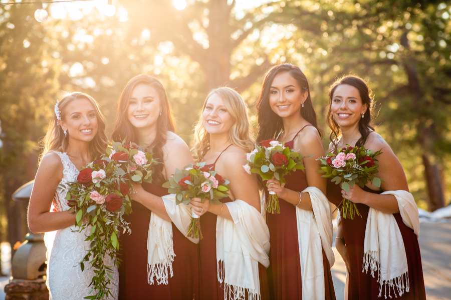 bride standing next to her 4 bridesmaids who are dressed in red in the mountains