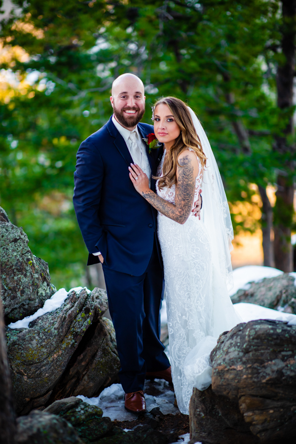 newlywed couple standing on rocks and looking at the camera