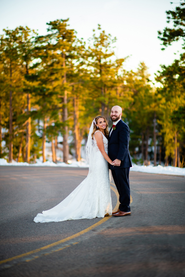 newlywed couple stopping on a secluded road and looking at the camera