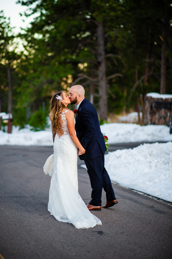 newlywed couple stopping on a secluded road to give each other a kiss