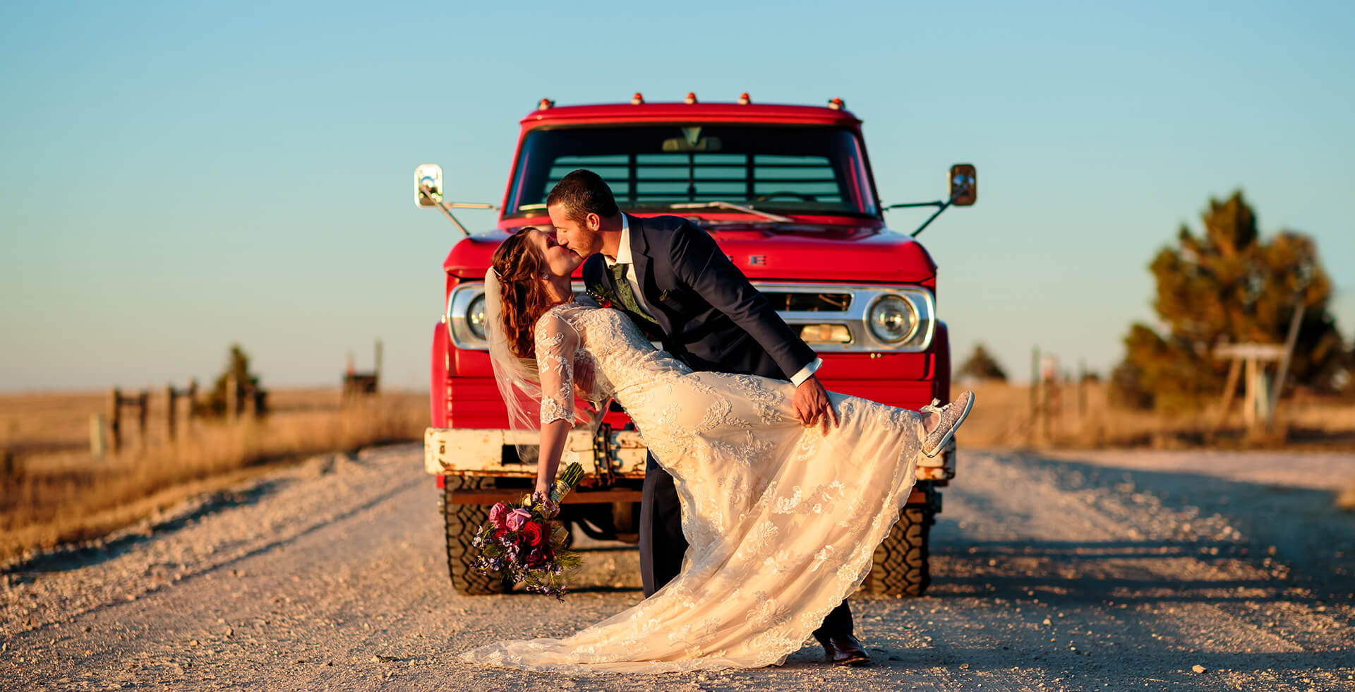 wedding couple kissing in front of a red truck