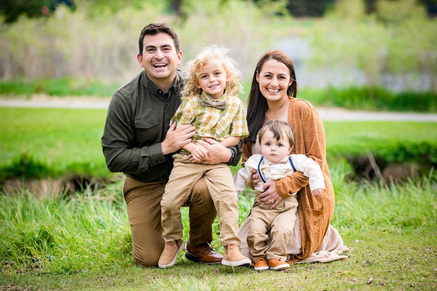family of 4 with two toddles sitting on the grass at a park